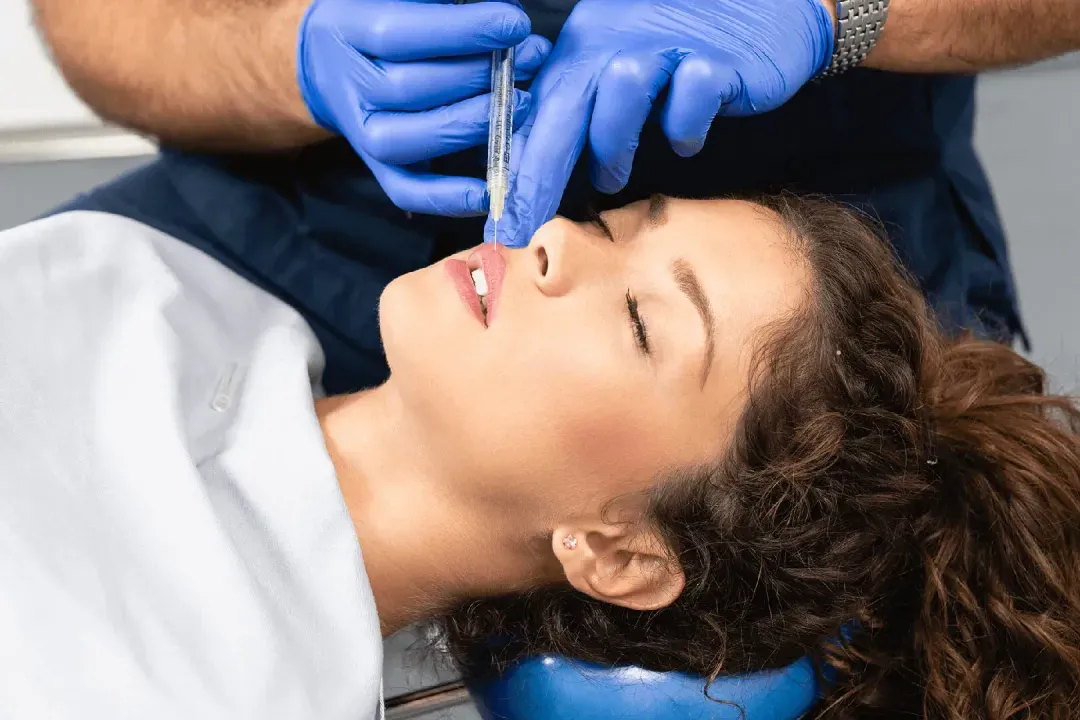Dentist in blue gloves examining patient's teeth during dental procedure in clinical setting.